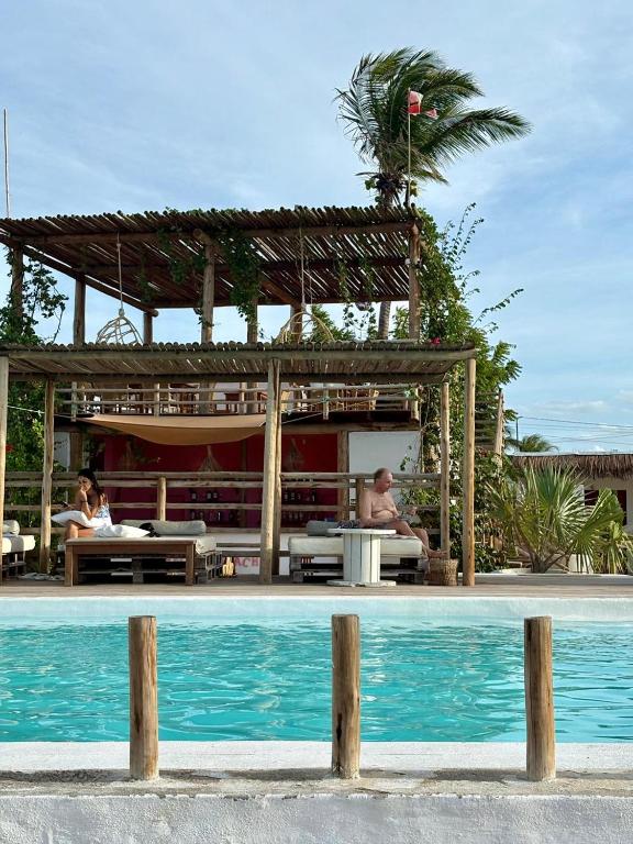 two people sitting at a table next to a pool at Amagali Beach Club in Galinhos