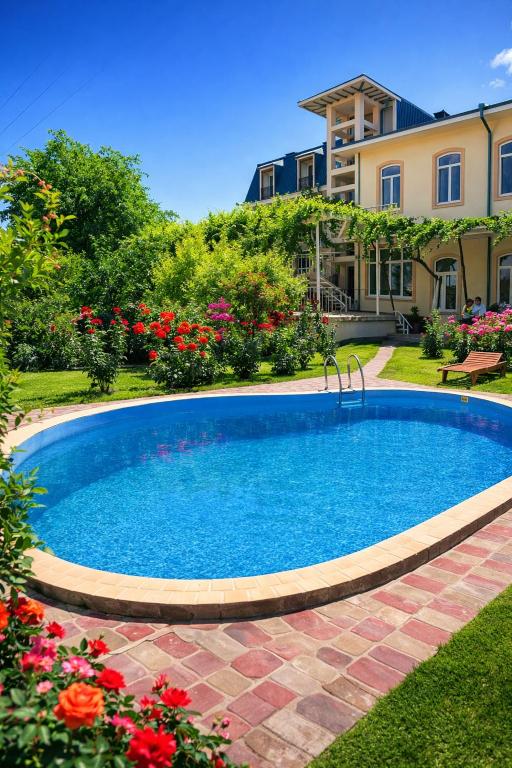 a swimming pool in front of a house with flowers at Hotel Latif Samarkand in Samarkand