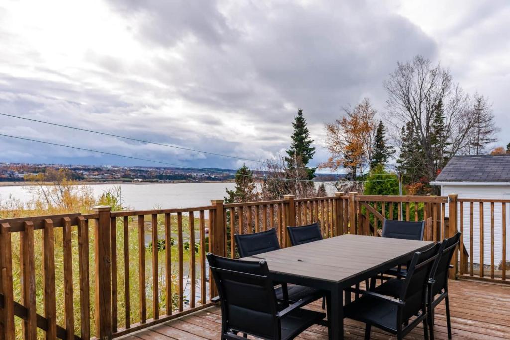 a wooden deck with a table and chairs on it at Hôtel à la maison - La Bleue Maritime in Rivière-du-Loup