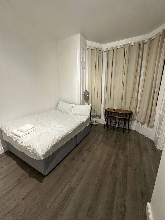 a white bedroom with a bed and a table at Spacious Flat White City in London