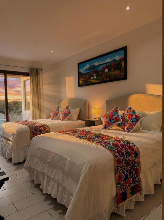 a hotel room with two beds and a tv on the wall at The Madevelyn in Atitlán in Panajachel