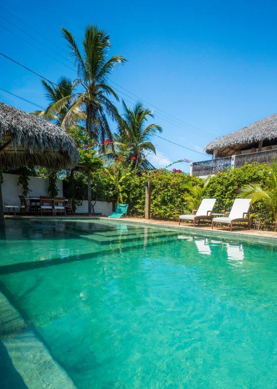 a swimming pool with blue water and palm trees at Atins - Vila Mani com piscina in Atins