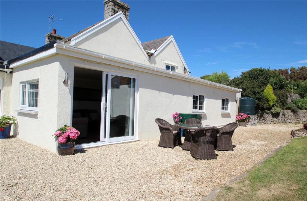 a patio with a table and chairs in front of a house at 1 Bed in Gower oc-hh80 in Oxwich