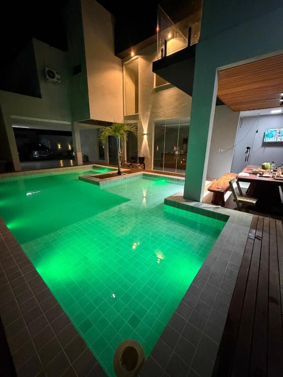 a swimming pool with green lighting in a building at Casa Itacimirim in Camacari