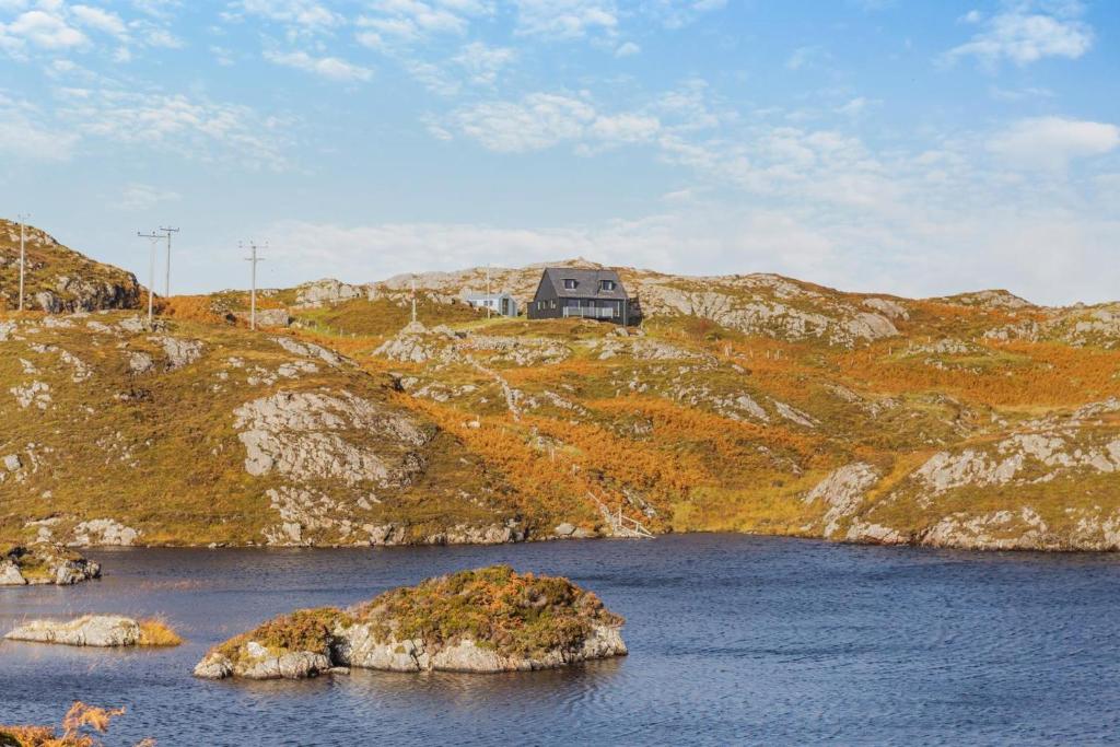 a house sitting on top of a hill with a body of water at 2 Bed in Lochinver oc-t30029 in Clachtoll