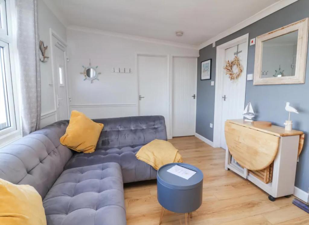 a living room with a blue couch and yellow pillows at 43 sea valley in Bideford