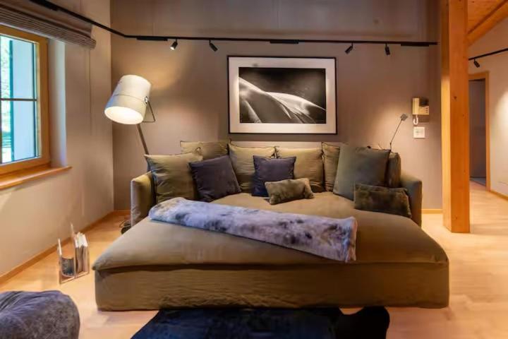 a large bed in a living room with a couch at Chalet Gutsch Andermatt in Andermatt
