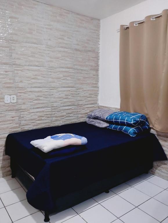 a room with a bed with blue sheets and pillows at casa 1 perto do pavilhão de Carapina a 8 kilometros do aeroporto in Serra