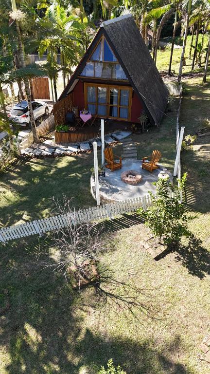 a small house with a thatched roof and a patio at Chalé do amor, sítio pousada vô Maneca in Timbó