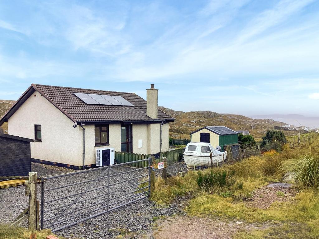a house with solar panels on the roof and a boat at At Last in Rhiconich
