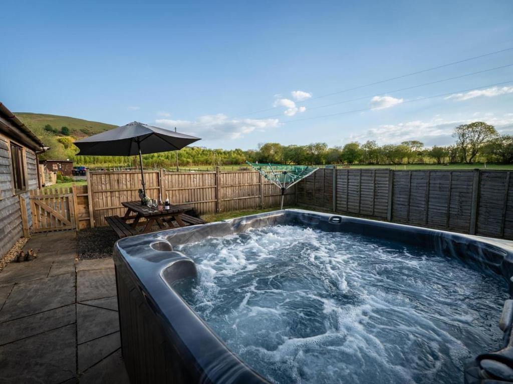 a hot tub on a patio with an umbrella at 2 Bed in Llandrindod Wells oc-88203 in Llandegley