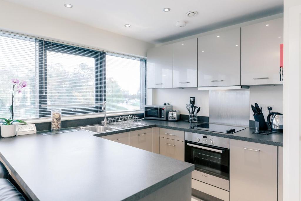 una cucina con armadi bianchi e piano di lavoro bianco di Room Space Service Apartments – New Manor House a Bracknell