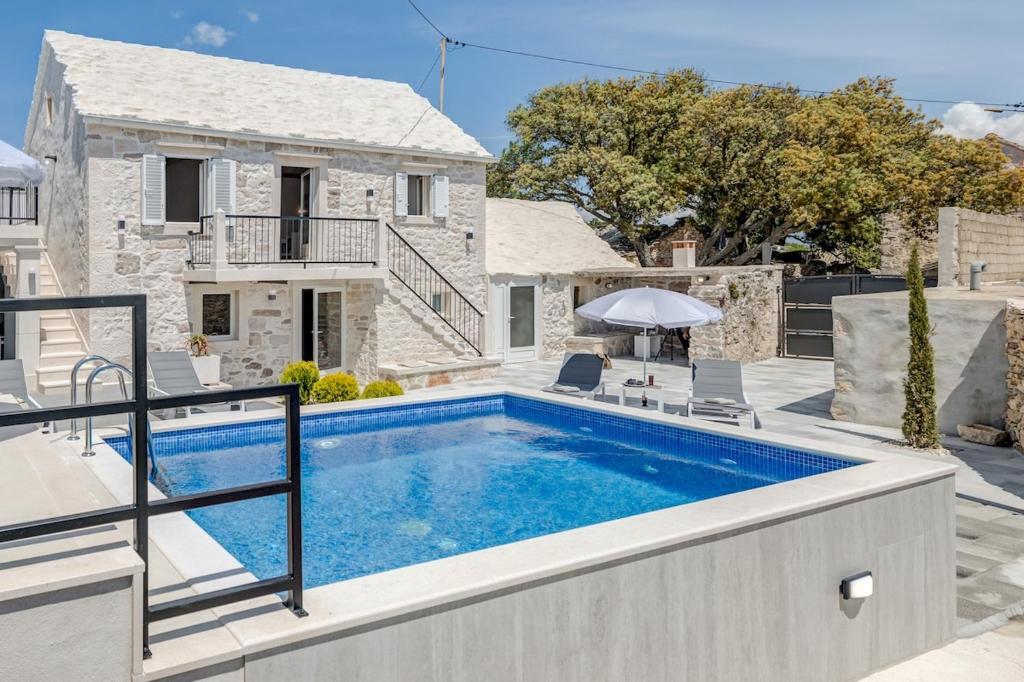 a villa with a swimming pool and a house at Authentic Dalmatian stone villa in Selca