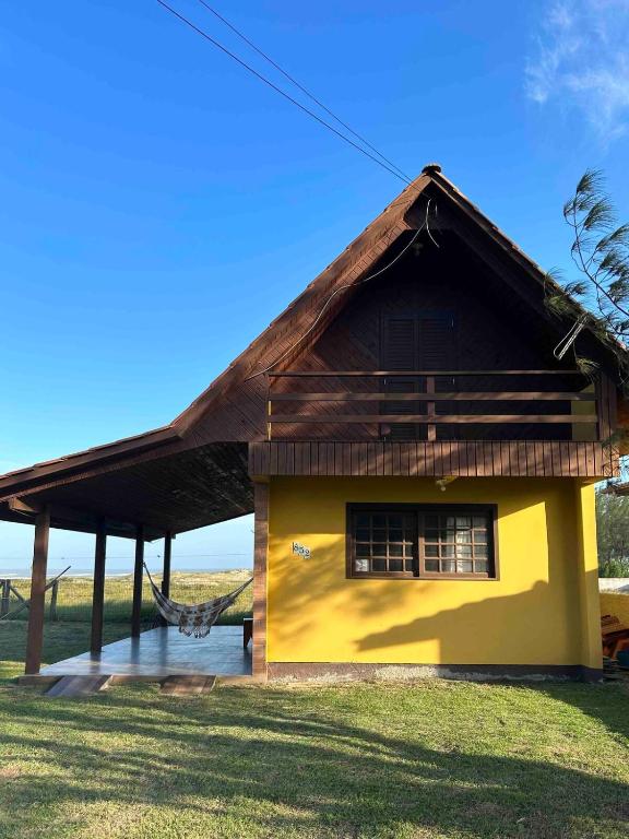 a small yellow house with a thatched roof at Chalé Horizonte do Silva in Arroio do Silva