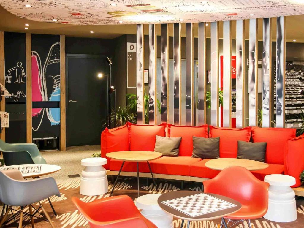 a lobby with a red couch and tables and chairs at Ibis Irun in Irún