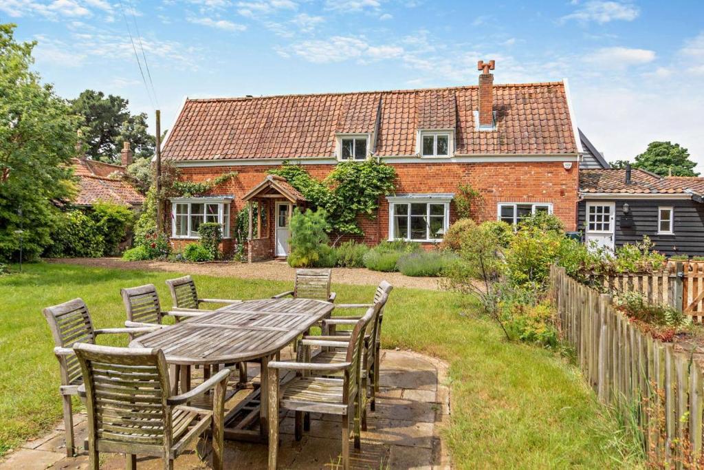 a wooden table and chairs in front of a house at 3 Bed in Snape oc-g29478 in Snape