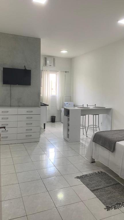 a white kitchen with a bed and a table at Kitnet Equipada in Sao Jose do Rio Preto