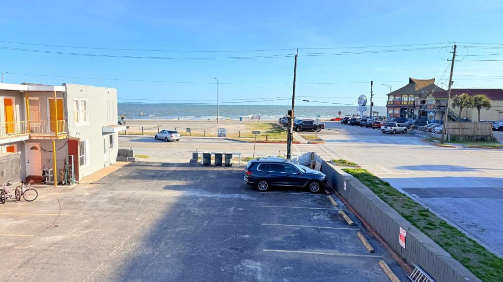 a car parked in a parking lot next to the beach at Beachtree Motel in Galveston