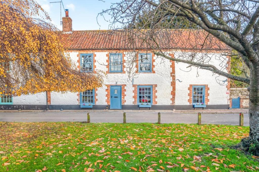 a white building with blue doors and a tree at 3 Bed in Thornham oc-983 in Thornham