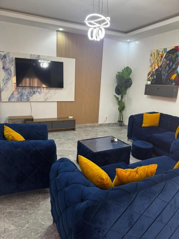 a living room with blue couches and a tv at Kantora Red almadie in Dakar