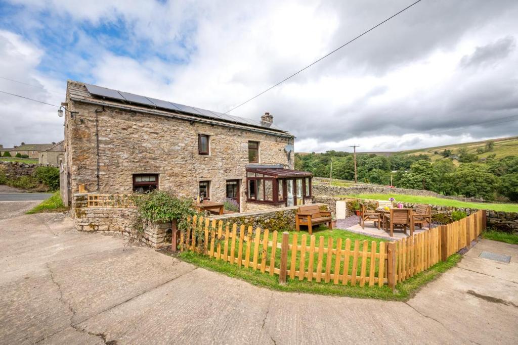 a stone house with a wooden fence in front of it at 2 Bed in Arkengarthdale oc-ds951 in Richmond