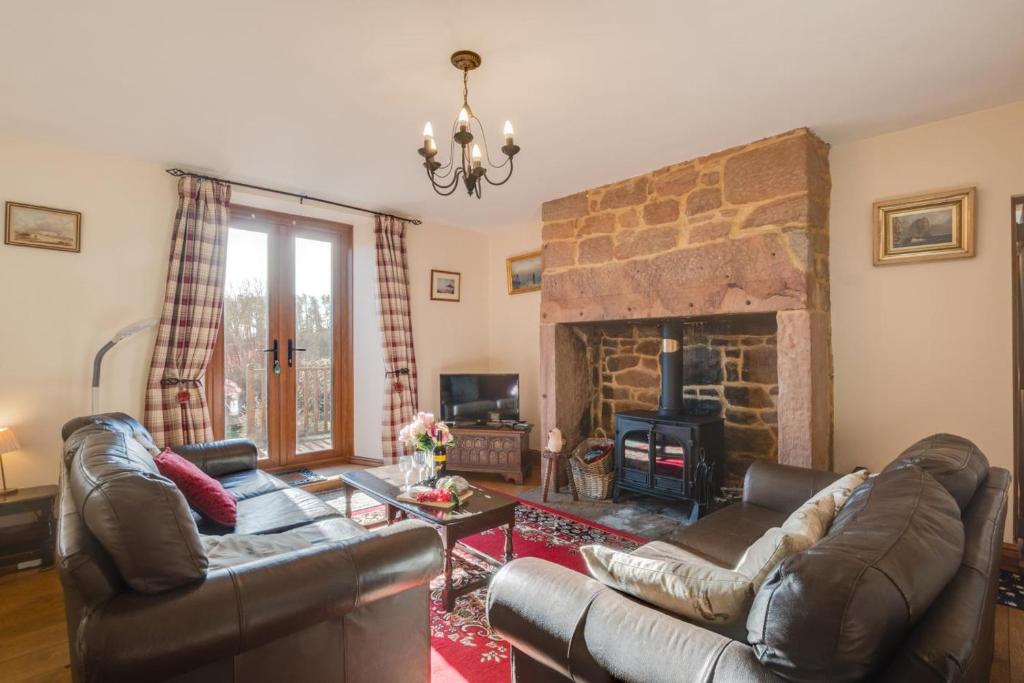 a living room with two leather couches and a fireplace at 2 Bed in Chatton oc-nb620 in Chatton