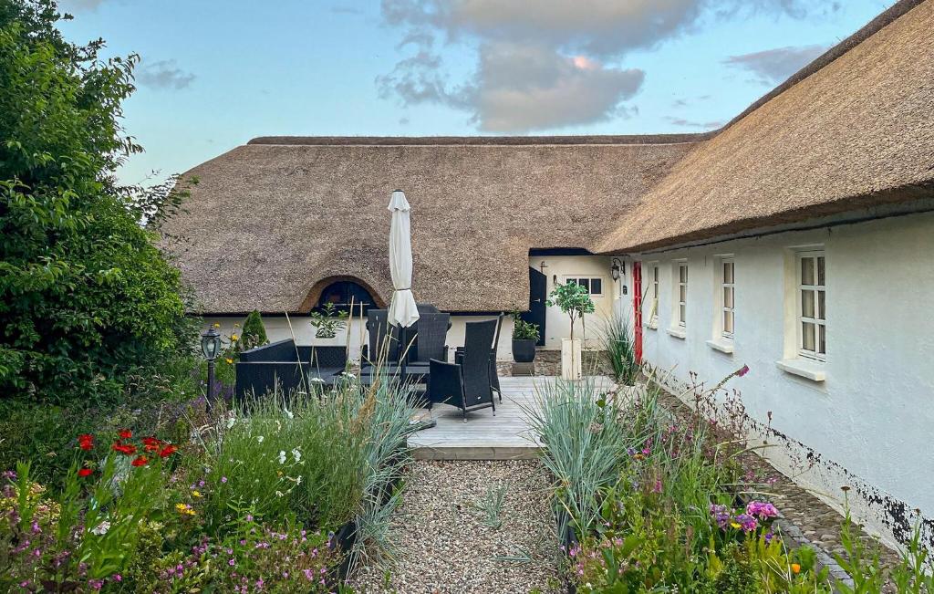 a house with a thatched roof and a patio with an umbrella at Amazing Home In Ulfborg With Kitchen in Ulfborg