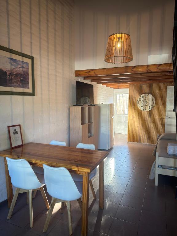 a kitchen with a wooden table and white chairs at Alvear centro hospedaje 2 in General Alvear