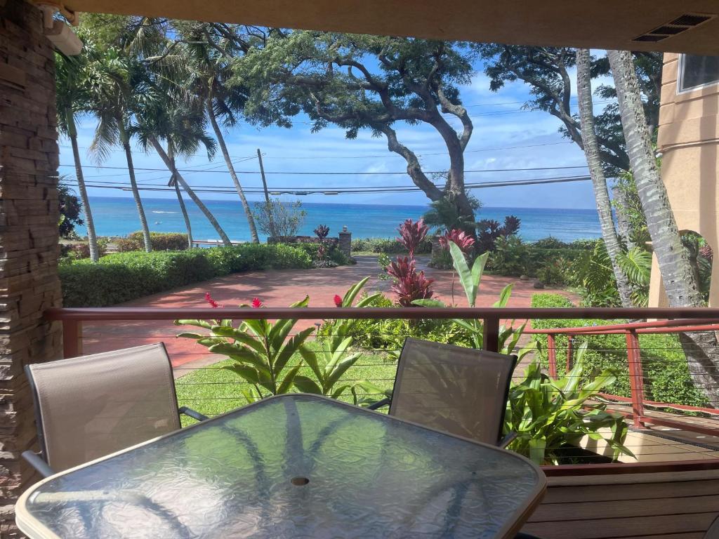 a table and chairs on a balcony with a view of the ocean at Maui Beach House B & B in Kahana