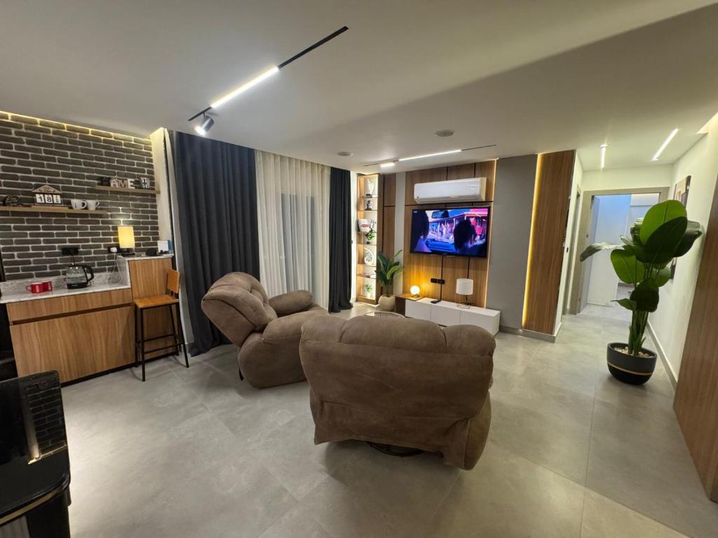 a living room with two chairs and a flat screen tv at Luxury 2BR Pool View Apartment Hotel Style in New cairo