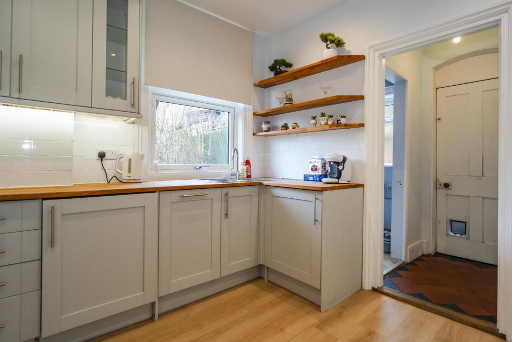 a kitchen with white cabinets and a window at Upper Grosvenor Suite in Royal Tunbridge Wells