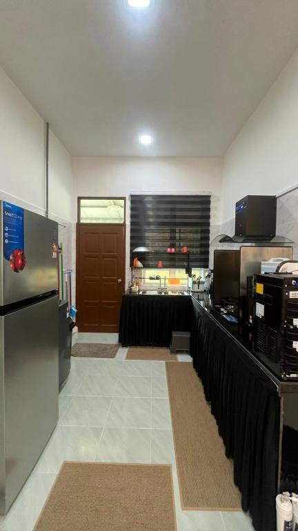 a kitchen with a counter with a refrigerator and a door at Paradise Homestay Marang in Marang