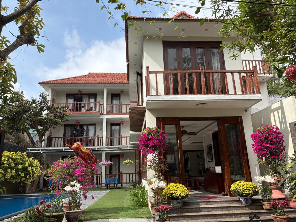 a house with flowers in front of a swimming pool at Village Moon Villa in Hoi An