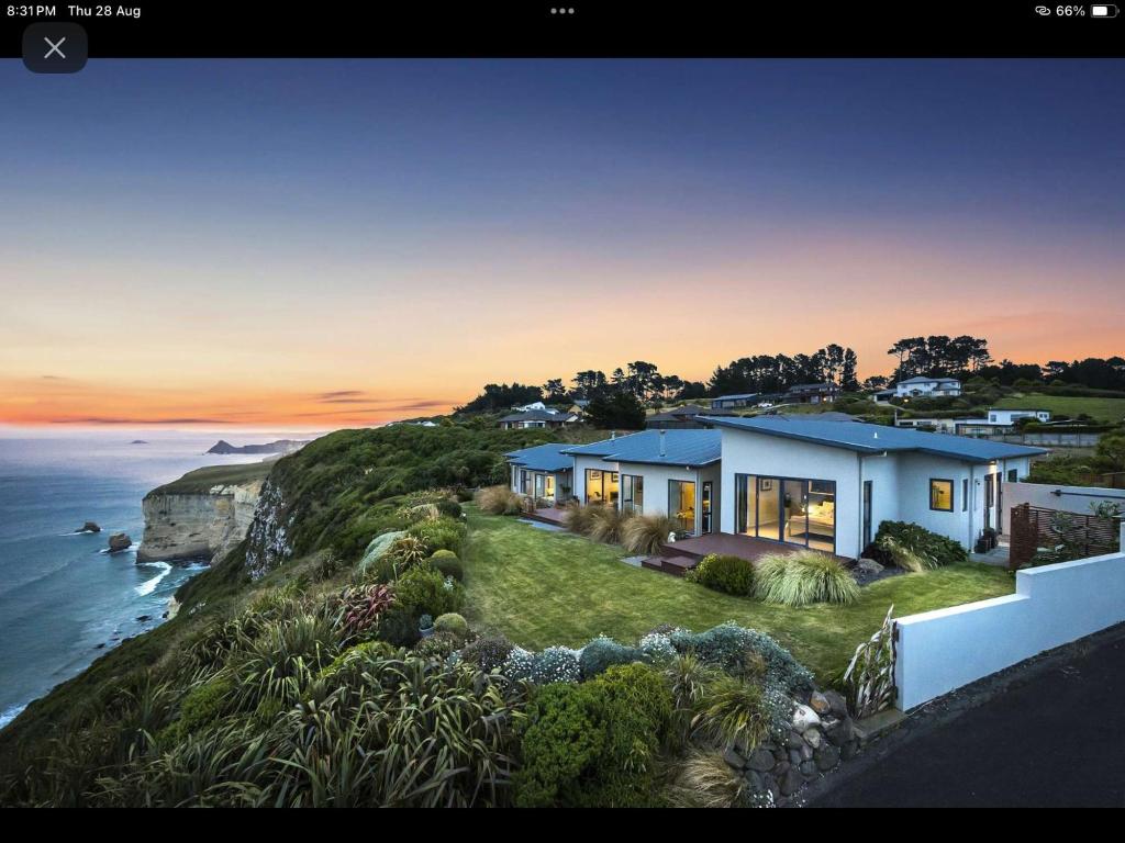 a house on a cliff next to the ocean at Oceanview Haven B&B in Dunedin