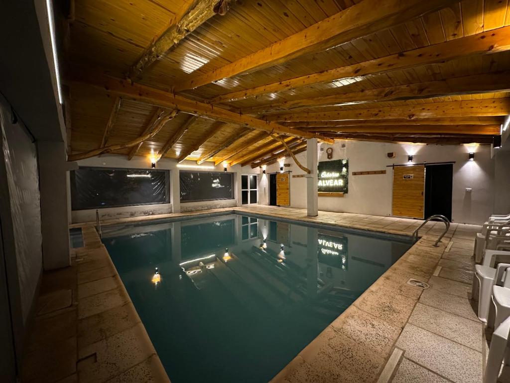 an indoor swimming pool with a wooden ceiling at Cabañas Alvear Piscina Climatizada in Huerta Grande