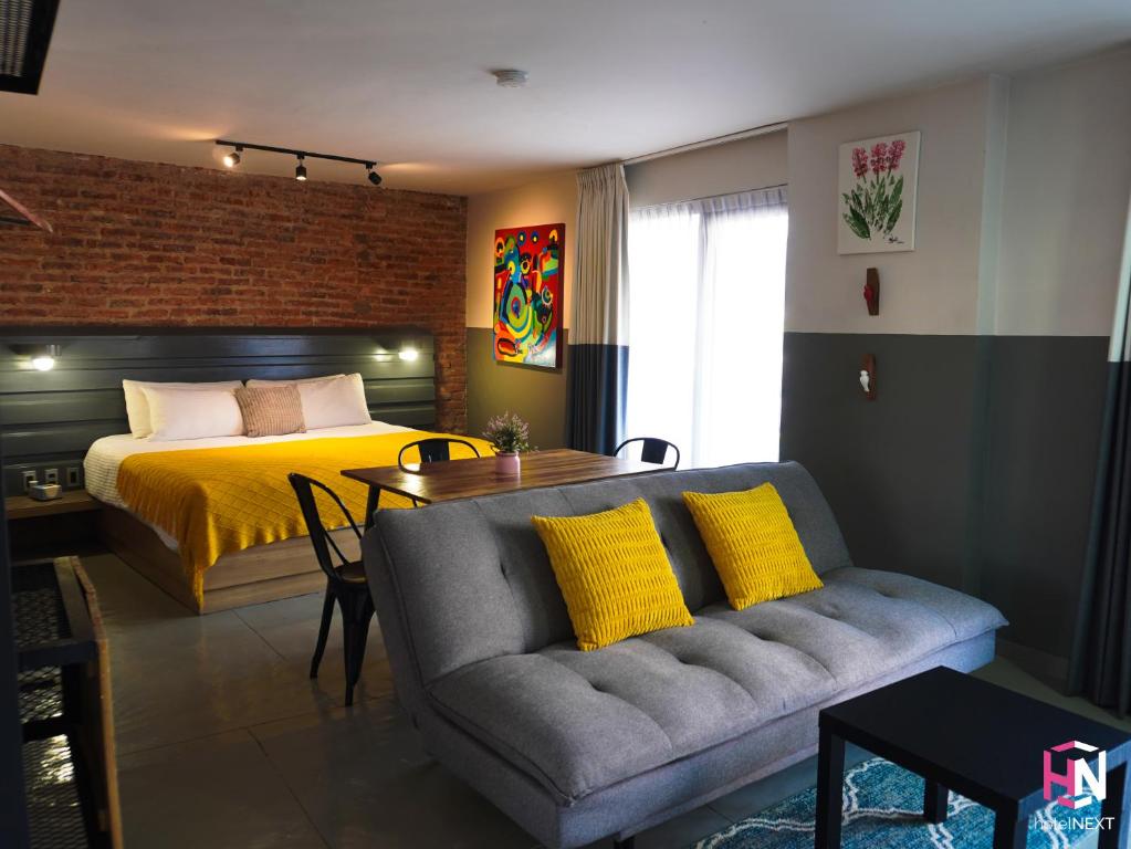 a bedroom with a bed and a couch and a table at Hotel NEXT Guadalajara in Guadalajara