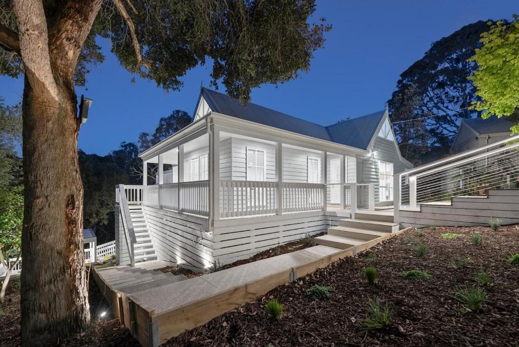 a white house with stairs and a tree at Marthas Tree Top Sanctuary in Mount Martha