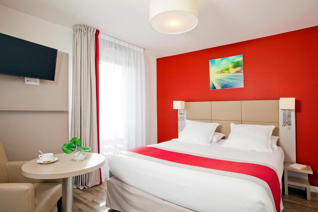 ein Schlafzimmer mit einem großen Bett und einer roten Wand in der Unterkunft Séjours & Affaires Paris Bagneux in Bagneux
