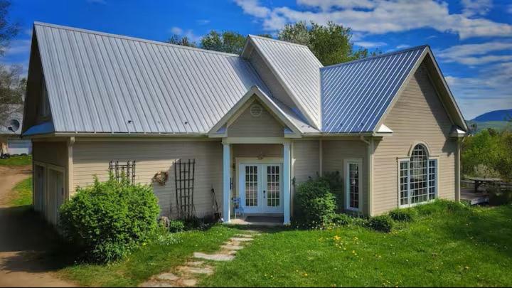 a small white house with a gambrel roof at Domaine des sentiers in Mansonville