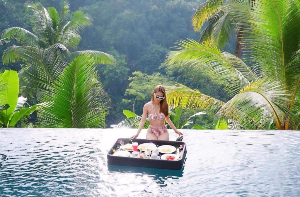 a woman in a bikini in a boat in the water at Secret Forest Hideaway near Ubud in Bangli