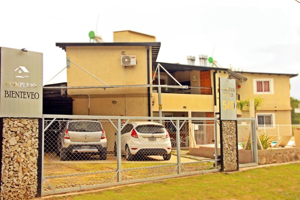 two cars parked in a parking lot behind a fence at Complejo Bienteveo in San Antonio de Arredondo