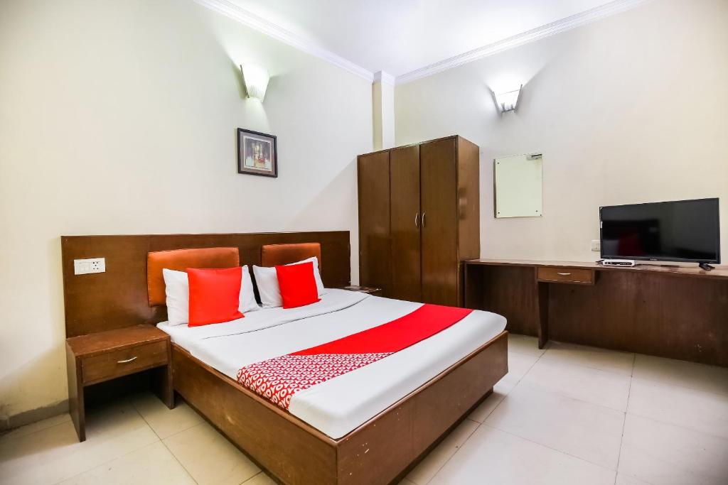 a bedroom with a bed with red pillows and a tv at Hotel O by OYO Angad Continental in Ambāla