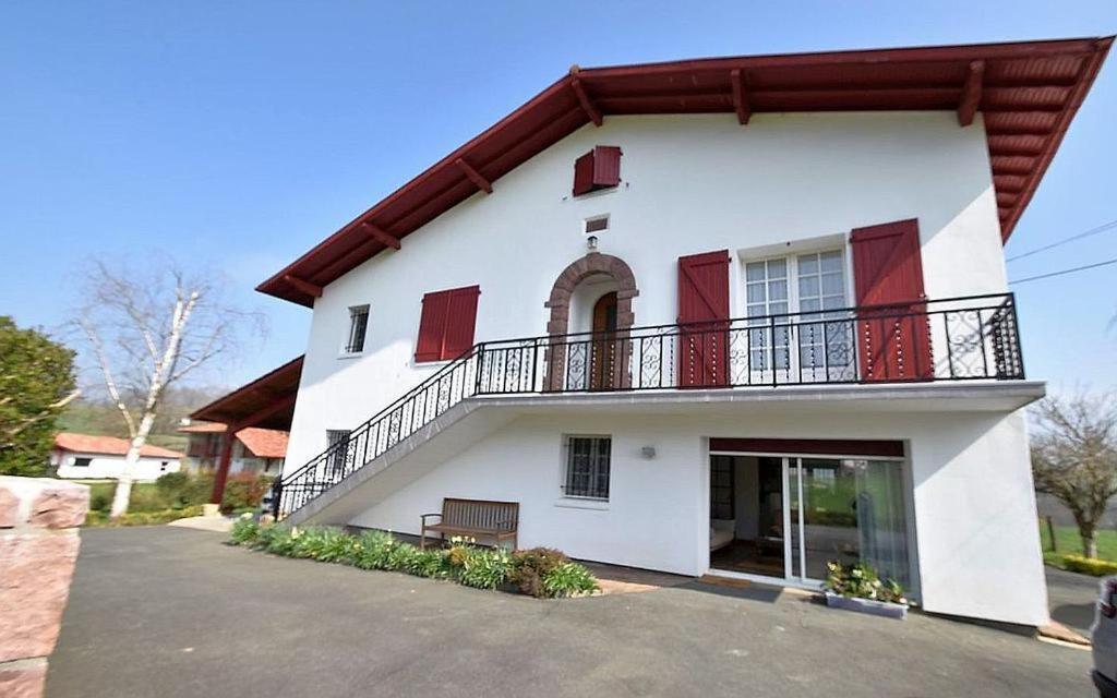 a white house with red shutters and a balcony at Ordokia in Lasse