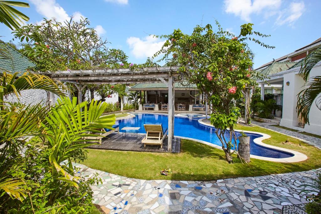 a backyard with a swimming pool and a house at Artemis Villa Hotel in Seminyak