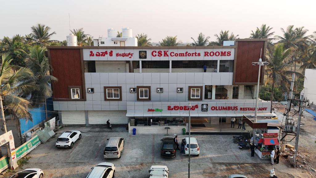 a building with cars parked in a parking lot at CSK Comforts in Tumkūr