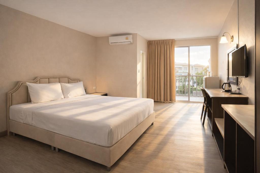 a bedroom with a bed and a desk and a television at Smile Bed Hotel in Sathani Khlong Rian