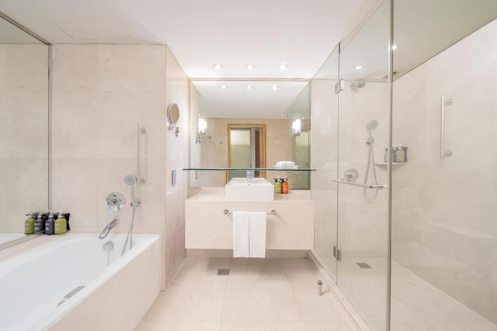 A marble bathroom with a bathtub, separate glass-enclosed shower and vanity.