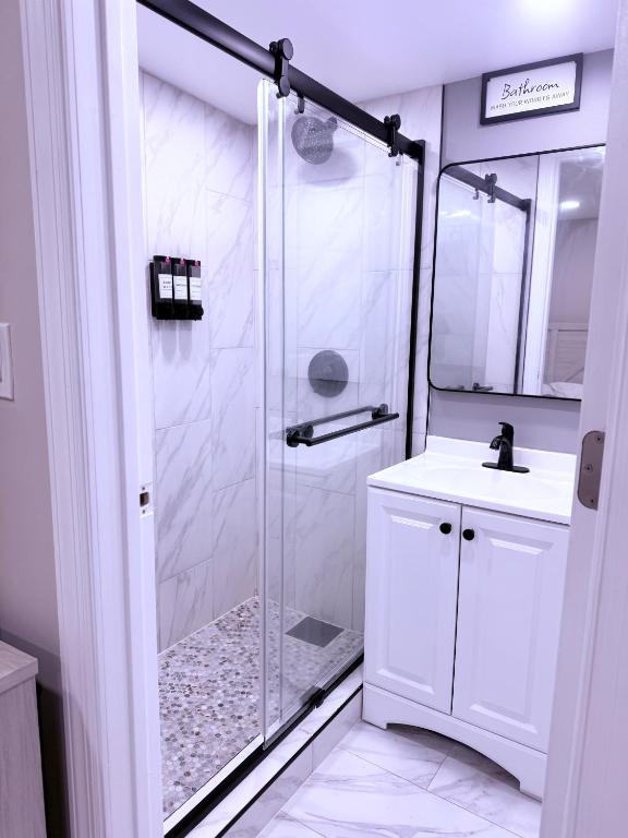 a white bathroom with a shower and a sink at Entire Private Studio JFK in Morris Park