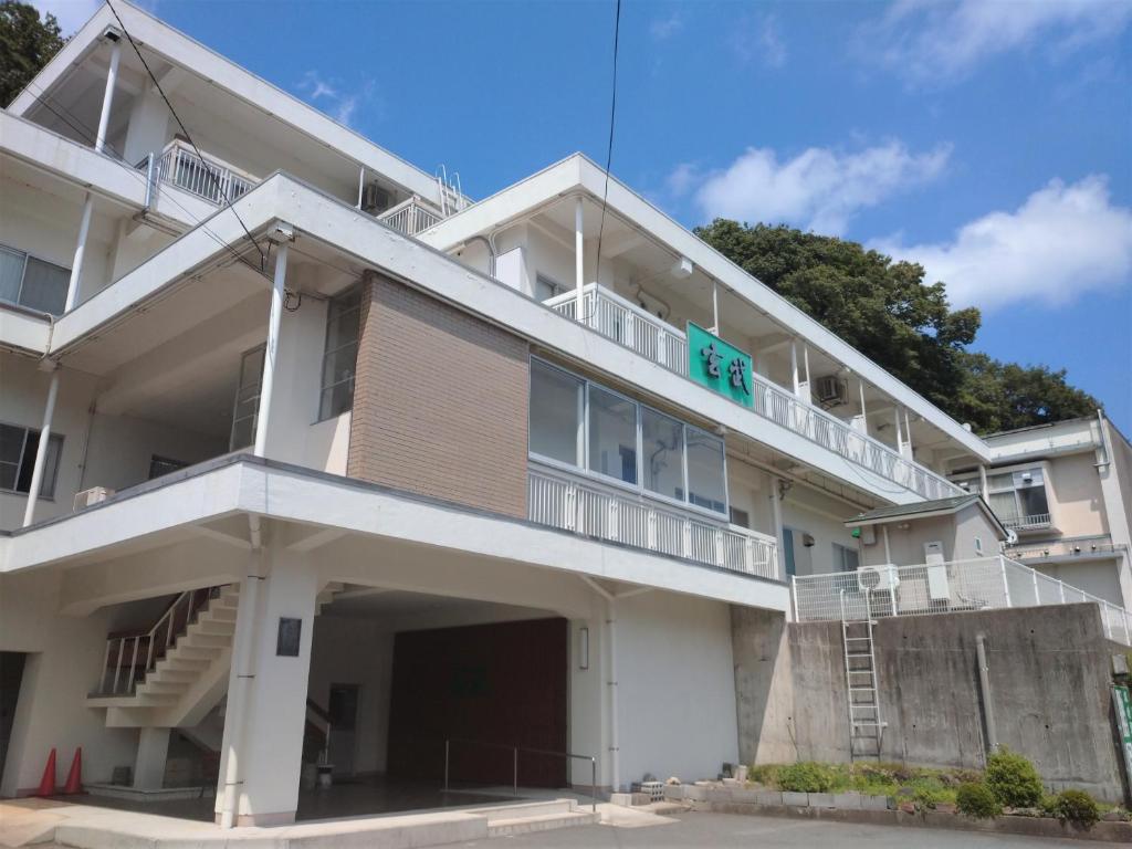 a white building with a green sign on it at KKR Kinosaki Genbu in Kinosaki