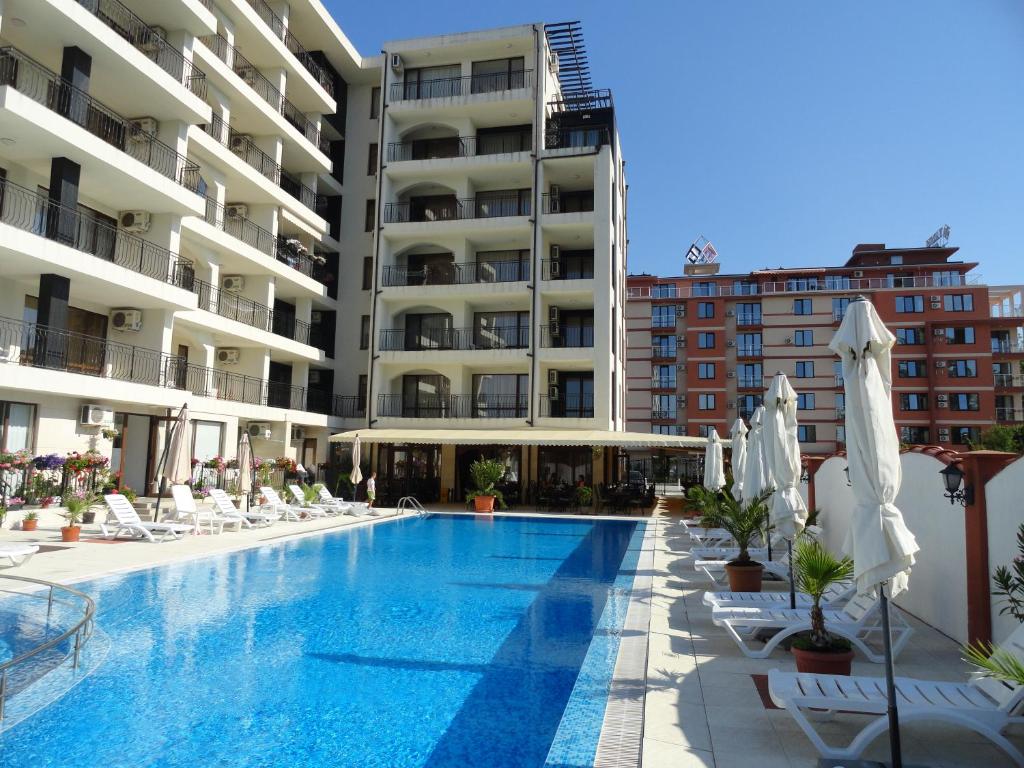 una piscina con sillas y sombrillas junto a un edificio en Cantilena Complex, en Sunny Beach